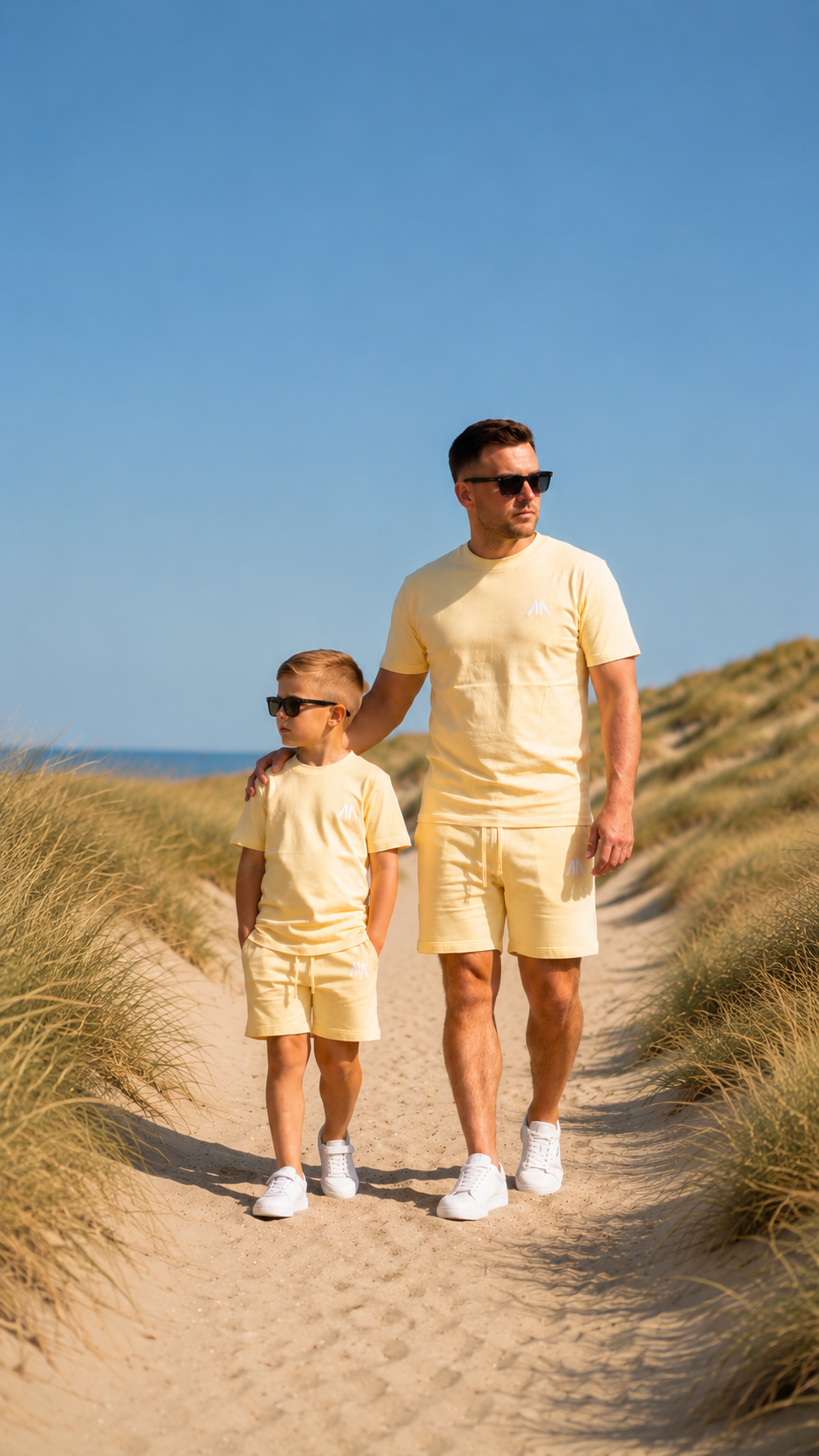 Vader en zoon in gele zomersets in de duinen