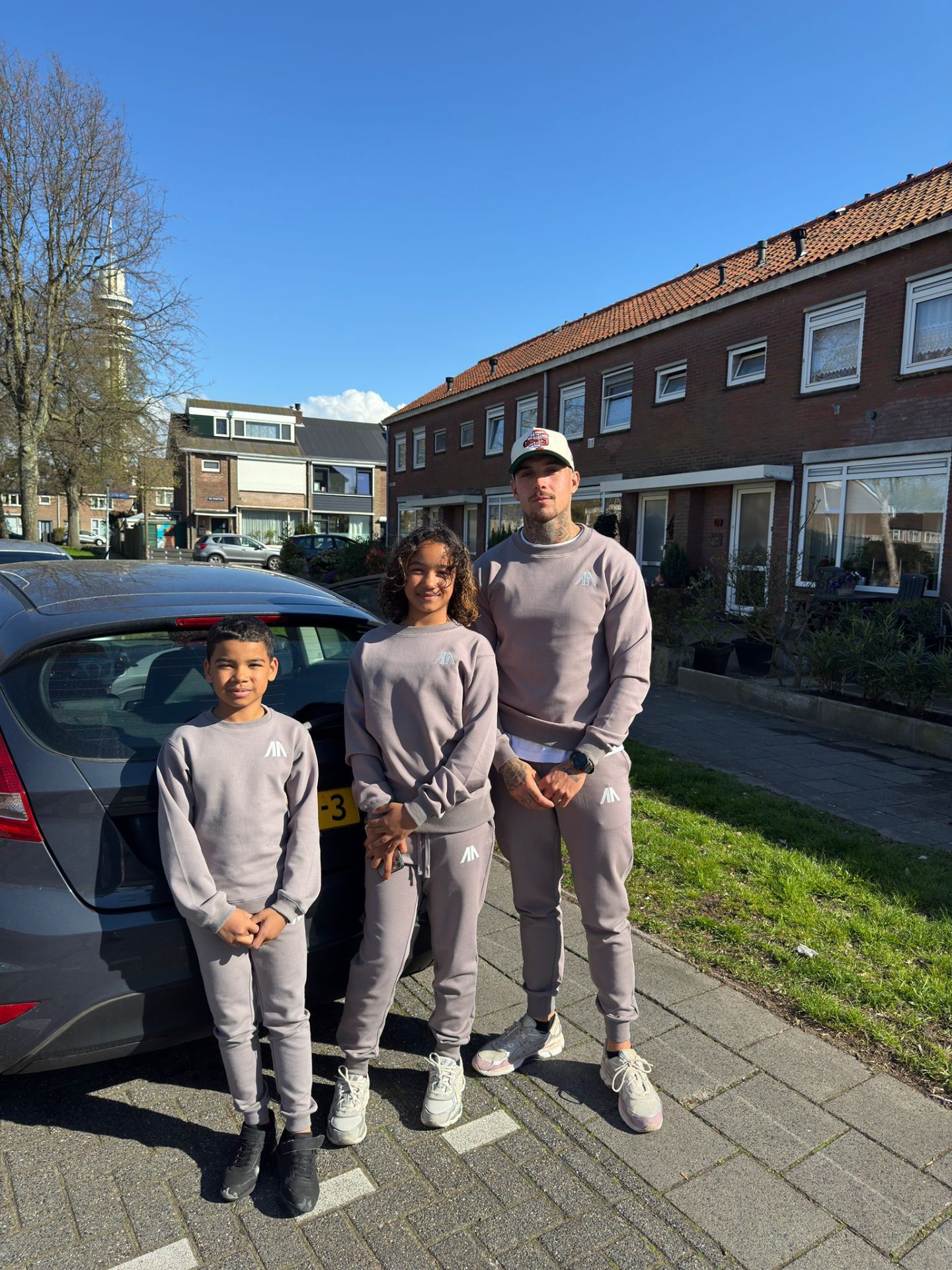 Vader met twee kinderen in matchende taupe sets op straat